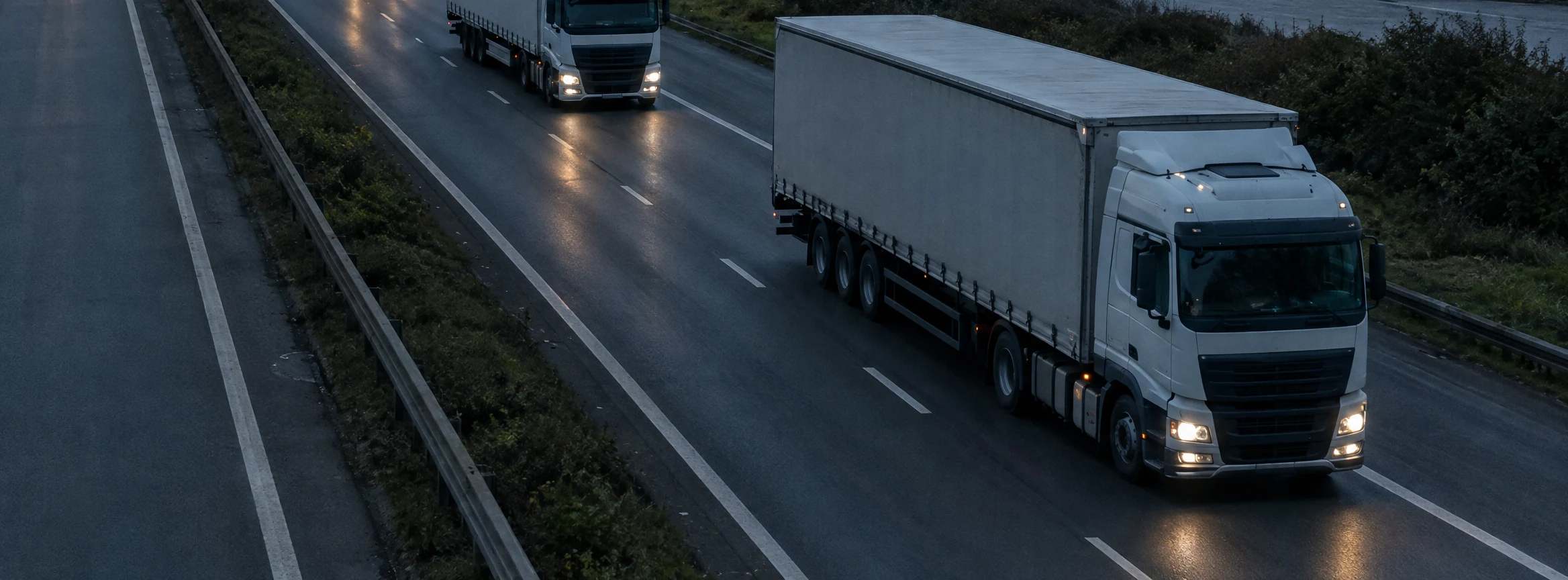 Sattelzüge mit Licht auf der Autobahn in der Dämmerung